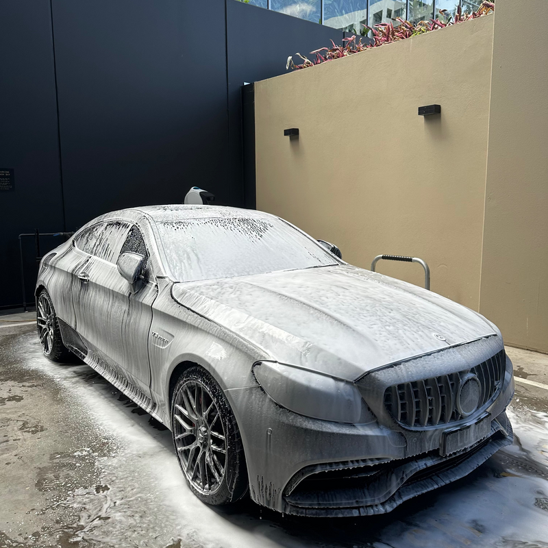 Car covered in soap suds parked next to a building
